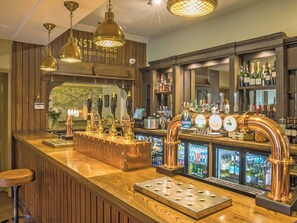 Eine Bar mit mehreren Bierhähnen, einer Registrierkasse und einer Auswahl an Spirituosenflaschen.