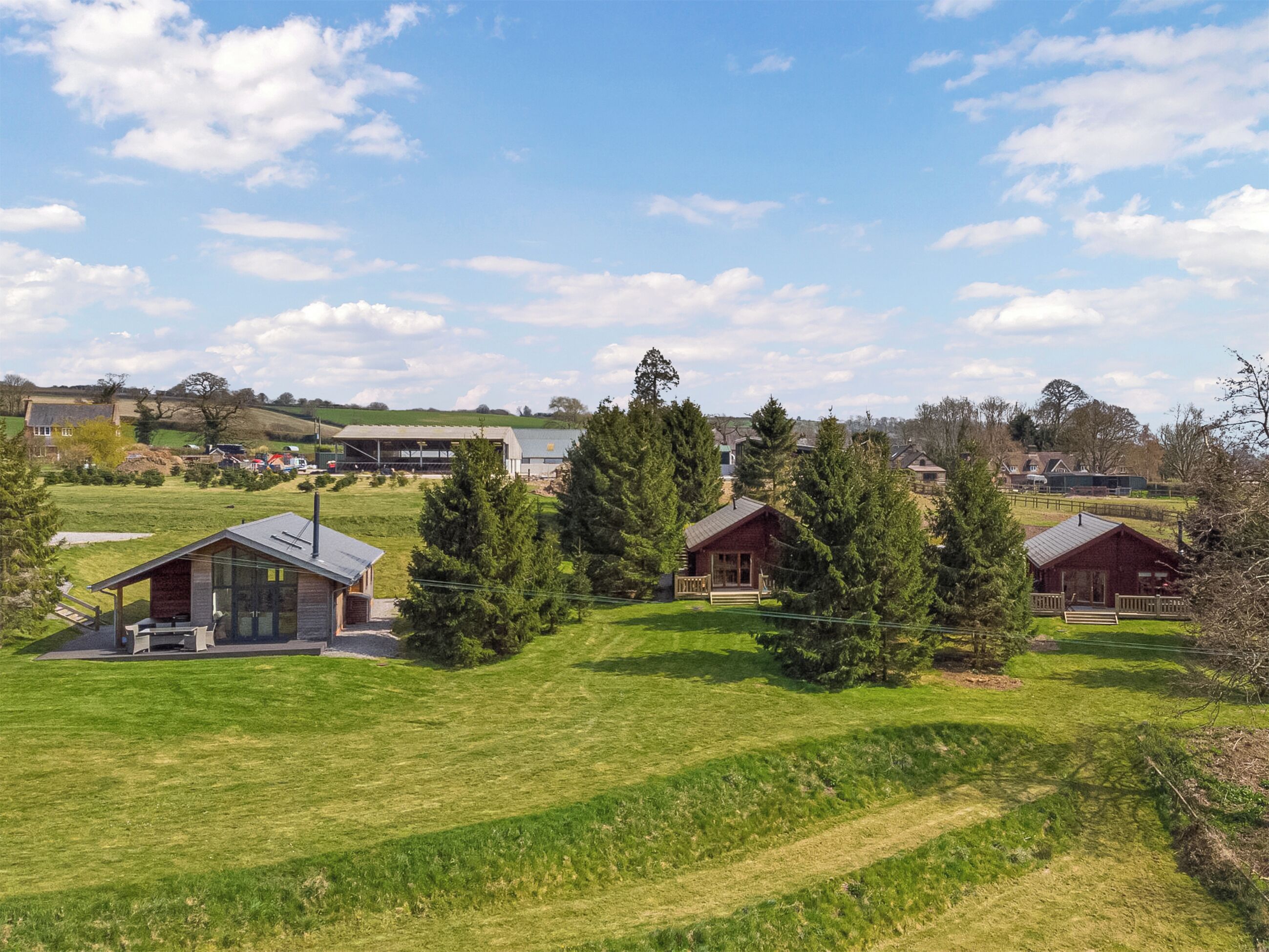 A rural landscape with several cabins surrounded by trees and open fields.