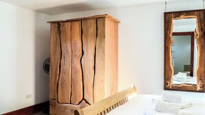 Un dormitorio con un armario de madera, una cama con ropa de cama blanca y un espejo grande con marco de madera.