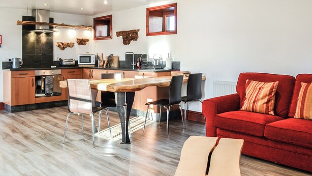 Una cocina moderna con comedor, un sofá rojo y una mesa de comedor de madera.