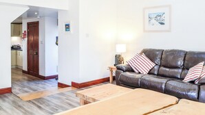 A living room with a leather sofa, wooden coffee table, and a framed picture on the wall. - Merrick Cottage - UK7783 (Newton Stewart)