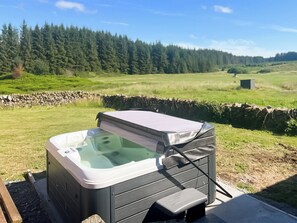 Ein Whirlpool in einer Außenanlage mit einer Steinwand und einem grünen Feld im Hintergrund.
