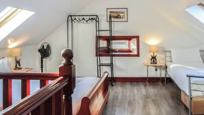 A dormitory room with a wooden bed, a desk, a chair, a ladder, a window, and a fan. - Merrick Cottage - UK7783 (Newton Stewart)