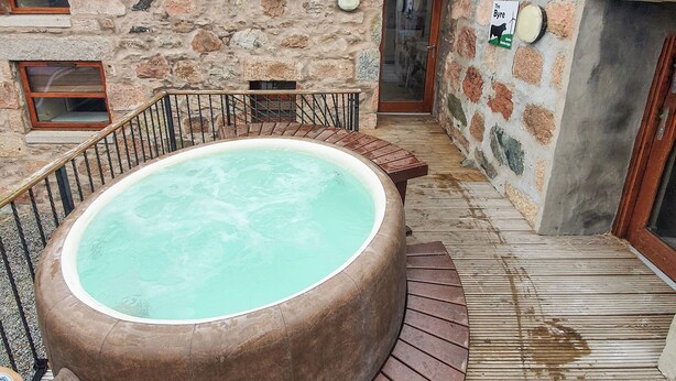 A stone building with a wooden deck, a hot tub, and a door with a sign. - 3 bedroom accommodation in Lumphanan, near Banchory (Lumphanan, near Banchory)