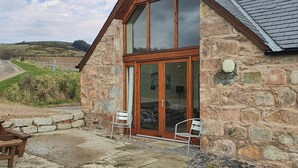 A stone building with a wooden gable roof and large glass doors. - 3 bedroom accommodation in Lumphanan, near Banchory (Lumphanan, near Banchory)
