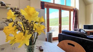A dining area with a table, chairs, and a vase of yellow flowers. - 3 bedroom accommodation in Lumphanan, near Banchory (Lumphanan, near Banchory)