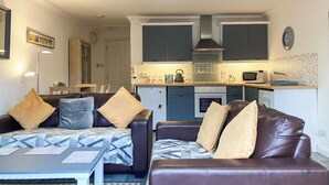 Un espacio habitable compacto con kitchenette, un conjunto de sofás y una zona de comedor.