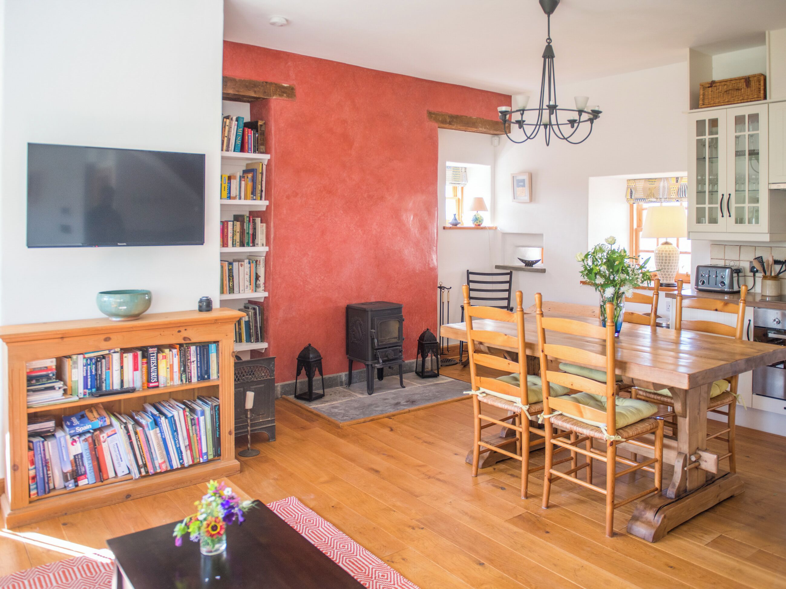 A cozy living room with a fireplace, wooden dining table, and bookshelves.