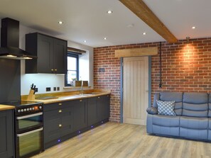 A modern kitchen with dark cabinetry, a wooden countertop, and a built-in oven. - 3 bedroom accommodation in Swafield, near North Walsham (Swafield, near North Walsham)