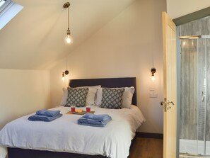 Ein ordentlich gemachtes Bett mit blauen Handtüchern, einem Kopfteil und zwei Wandleuchten.