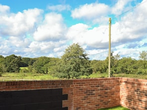 A brick wall with a metal fence and a utility pole in a rural setting. - 3 bedroom accommodation in Swafield, near North Walsham (Swafield, near North Walsham)