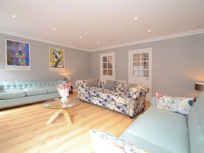 A living room with a light blue sofa, a floral sofa, and a glass coffee table. - 3 bedroom accommodation in York (York)