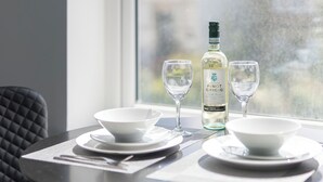 A dining table with two white bowls, two wine glasses, and a bottle of Pinot Grigio wine. - Coastal Gem - UK2773 (Llandudno)