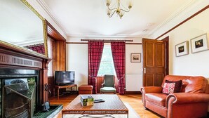 Ein Wohnzimmer mit Kamin, Fernseher, Sofa und Couchtisch.