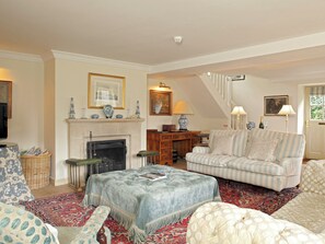 Ein Wohnzimmer mit Kamin, einer Couch, einem gemusterten Teppich und einem Fernseher.