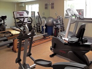 Ein Fitnessstudio mit verschiedenen Trainingsgeräten, darunter Laufbänder, Crosstrainer und Kraftgeräte.