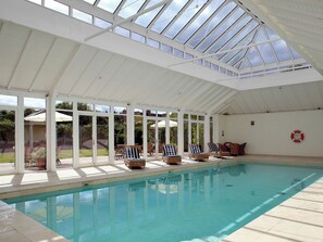 An indoor swimming pool with a glass ceiling, lounge chairs, and a lifebuoy on the wall. - Cheltenham - UKC1155 (Bruern, near Chipping Norton)