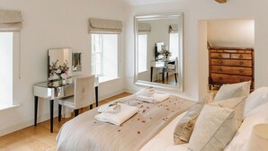 A bedroom with a bed, a dresser, a vanity with a mirror, and a window. - 4 bedroom accommodation in Longframlington, near Rothbury (Longframlington, near Rothbury)