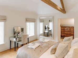 A bedroom with a bed, a dresser, a vanity with a mirror, and a window. - 4 bedroom accommodation in Longframlington, near Rothbury (Longframlington, near Rothbury)