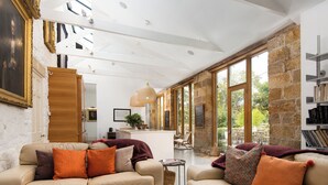 A spacious living area with two beige sofas, a wooden coffee table, and a stone wall. - 4 bedroom accommodation in Longframlington, near Rothbury (Longframlington, near Rothbury)