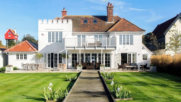 A large, two-story house with a wooden deck leading to the entrance, surrounded by a well-maintained lawn and garden. - 1 bedroom accommodation in Thorpeness, near Aldeburgh (Thorpeness, near Aldeburgh)