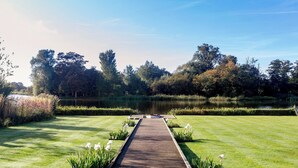 A wooden pathway leading to a pond, surrounded by well-maintained grass and trees. - 1 bedroom accommodation in Thorpeness, near Aldeburgh (Thorpeness, near Aldeburgh)