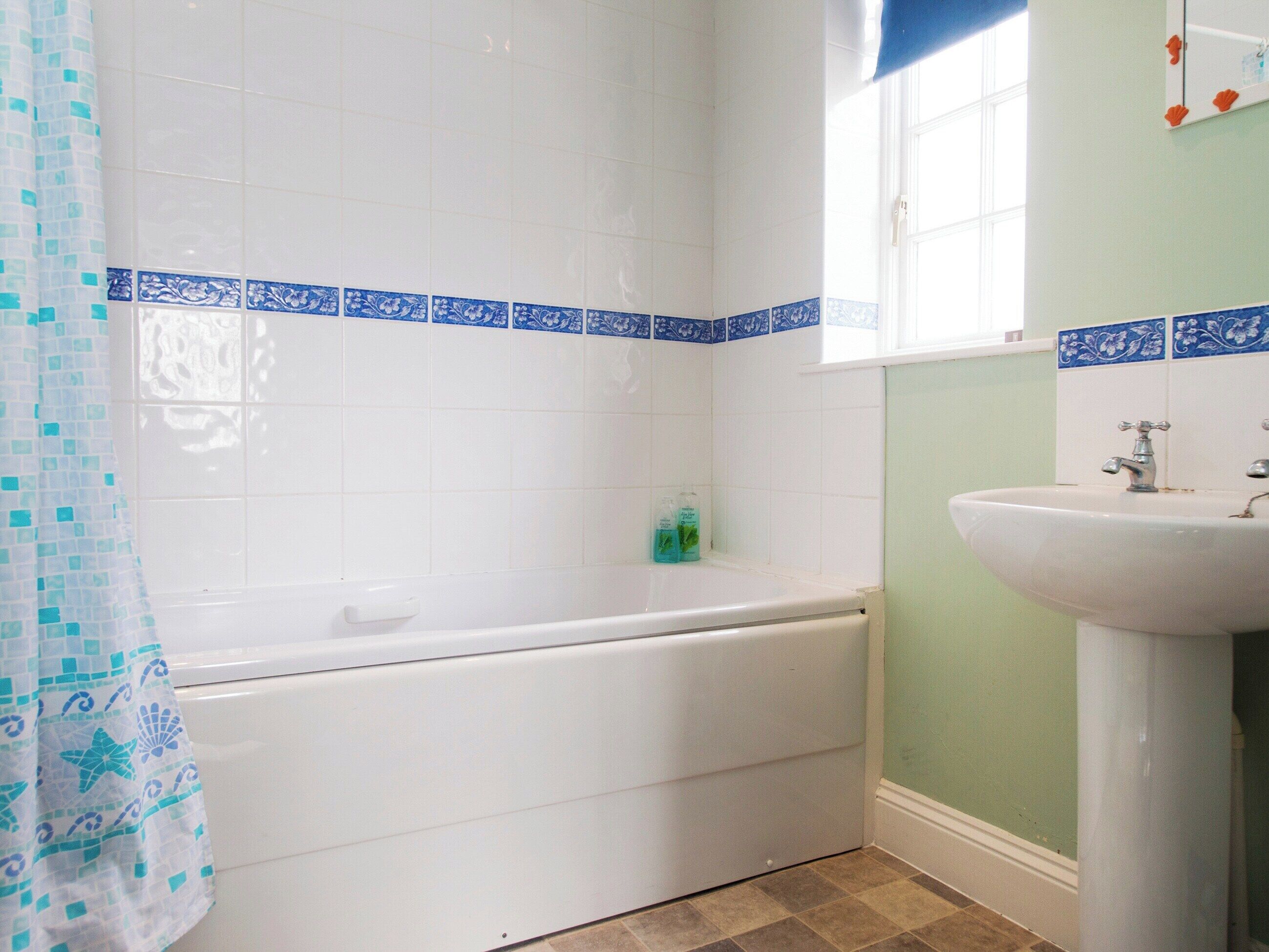 A bathroom with a bathtub, a sink, and a window.