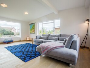 A modern living room with a grey sofa, a blue patterned rug, and a map on the wall. - 3 bedroom accommodation in Thorpeness, near Aldeburgh (Thorpeness, near Aldeburgh)