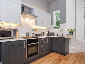 Eine moderne Küche mit grauen Schränken, einer Edelstahl-Mikrowelle, einem Backofen und einem Spülbecken.