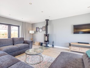 A modern living room with a grey sofa, a glass coffee table, a fireplace, and a flat-screen TV. - 5 bedroom accommodation in Dunholme, near Lincoln (Dunholme, near Lincoln)