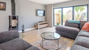 A modern living room with a fireplace, a sofa, a coffee table, and a TV mounted on the wall. - 5 bedroom accommodation in Dunholme, near Lincoln (Dunholme, near Lincoln)
