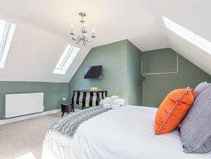 A bedroom with a sloped ceiling, a chandelier, a bed with pillows, a bedside table with a tray of fruit, and a radiator. - 5 bedroom accommodation in Dunholme, near Lincoln (Dunholme, near Lincoln)