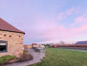 A brick house with a patio, a small deck, and a grassy yard. - 5 bedroom accommodation in Dunholme, near Lincoln (Dunholme, near Lincoln)