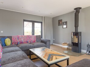 A modern living room with a sofa, a coffee table, a fireplace, and a window. - 5 bedroom accommodation in Dunholme, near Lincoln (Dunholme, near Lincoln)