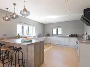 A modern kitchen with a central island, bar stools, pendant lighting, and a view of the outdoors. - 5 bedroom accommodation in Dunholme, near Lincoln (Dunholme, near Lincoln)