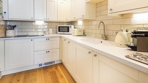 A kitchen with white cabinets, a microwave, a toaster, and a sink. - Fabulous luxurious bolthole in the centre of Inverness. (Inverness)