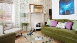 A living room with a green sofa, a white fireplace, a green side table, and a glass coffee table. - Fabulous luxurious bolthole in the centre of Inverness. (Inverness)