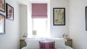 A bedroom with a bed, a window with a view, a lamp, and framed pictures on the walls. - Fabulous luxurious bolthole in the centre of Inverness. (Inverness)