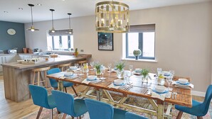 Une cuisine moderne avec un îlot central en bois, des chaises bleues et une table à manger dressée pour six personnes.