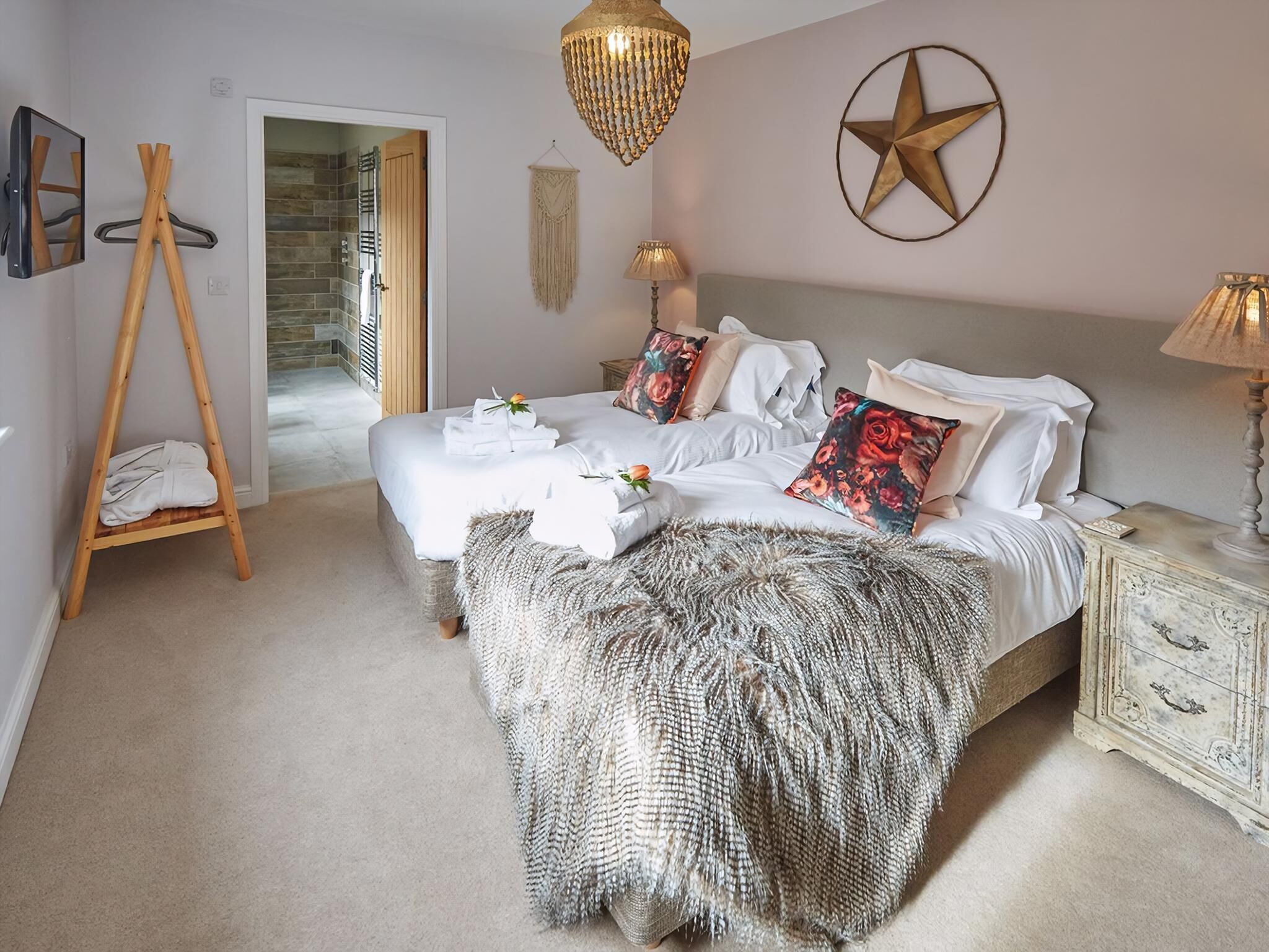 Quarto com cama, mesas de cabeceira, luminária pendente e decoração de parede com estrelas.