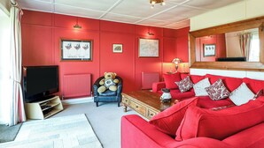 Una sala de estar con un sofá rojo, un televisor y un oso de peluche.