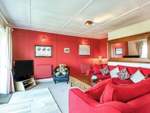 Ein Wohnzimmer mit einem roten Sofa, einem Fernseher und einem Teddybären.