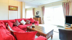 Una sala de estar con un sofá rojo, una mesa de centro de madera y un televisor.