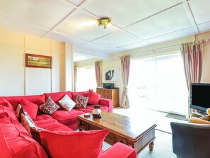 Ein Wohnzimmer mit einem roten Sofa, einem Holztisch und einem Fernseher.