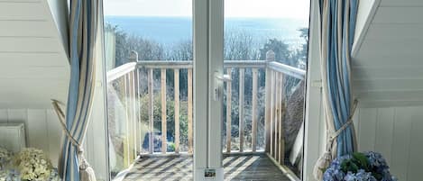 Une pièce avec vue sur la mer, accessible par un ensemble de portes vitrées.