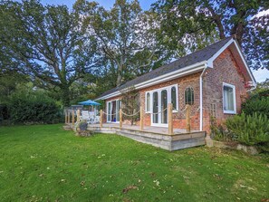 A brick building with a covered patio area, a small garden, and a blue umbrella. - 2 bedroom accommodation in Wootton Bridge (Wootton Bridge)