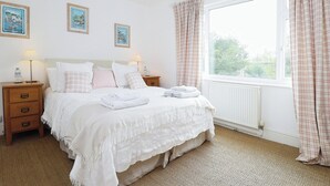 A neatly arranged bedroom with a bed, bedside tables, and a window with curtains.