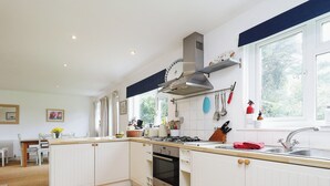 A modern kitchen with white cabinets, a gas stove, and a stainless steel sink.