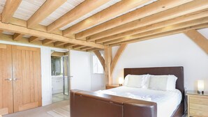Ein Schlafzimmer mit Holzboden, einem großen Bett, einem Nachttisch und einem Kleiderschrank.