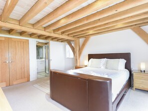 A bedroom with a wooden ceiling, a large bed, a nightstand, and a wardrobe. - 4 bedroom accommodation in Bembridge (Bembridge)